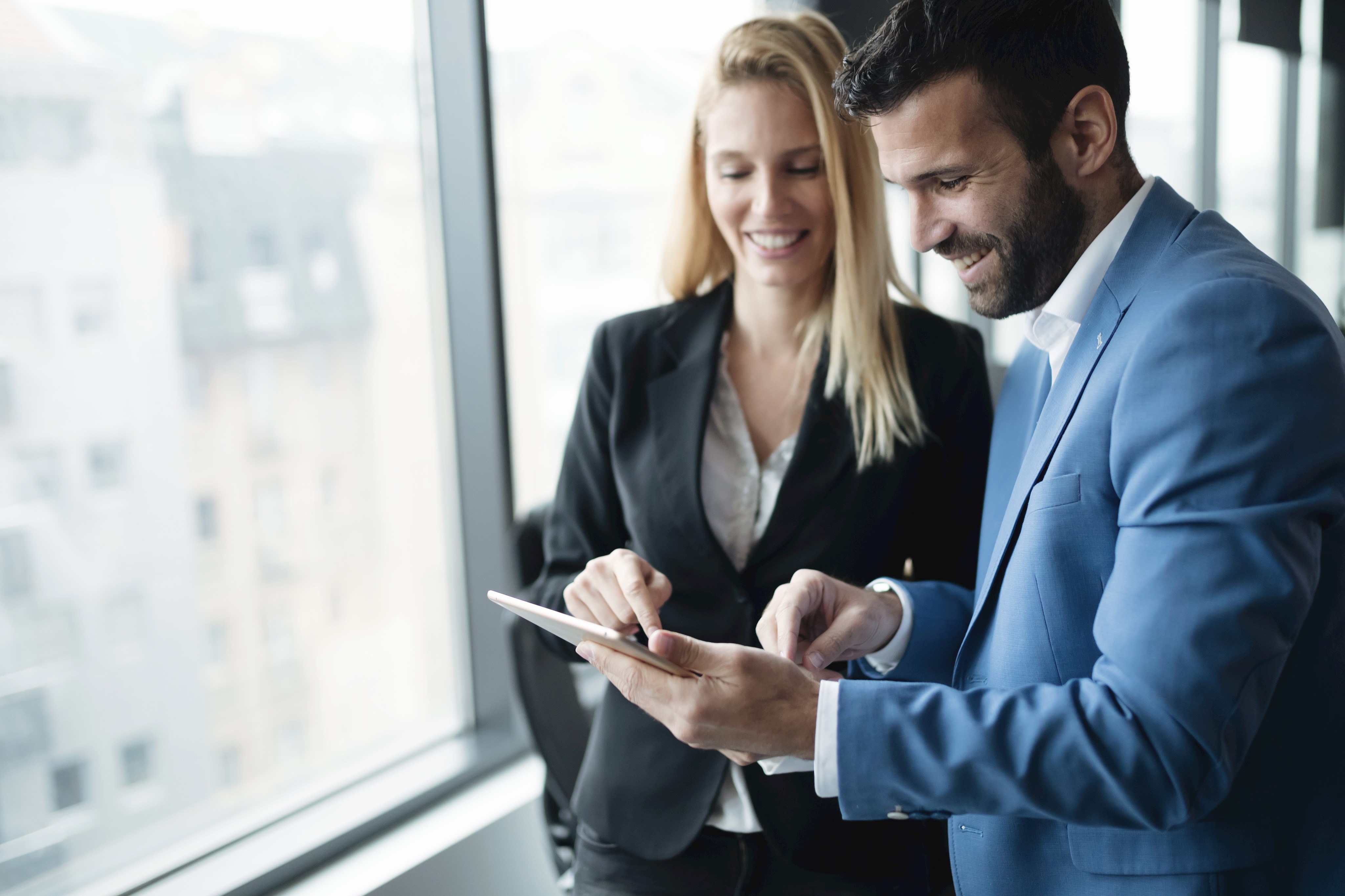 Glückliche Geschäftskollegen im modernen Büro mit Tablet